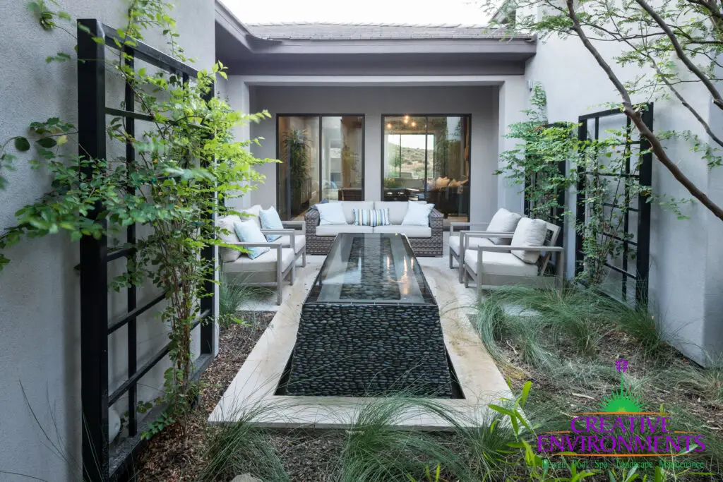 Custom metal trellis with Ivy, black pebble stone water feature and multiple seating areas.