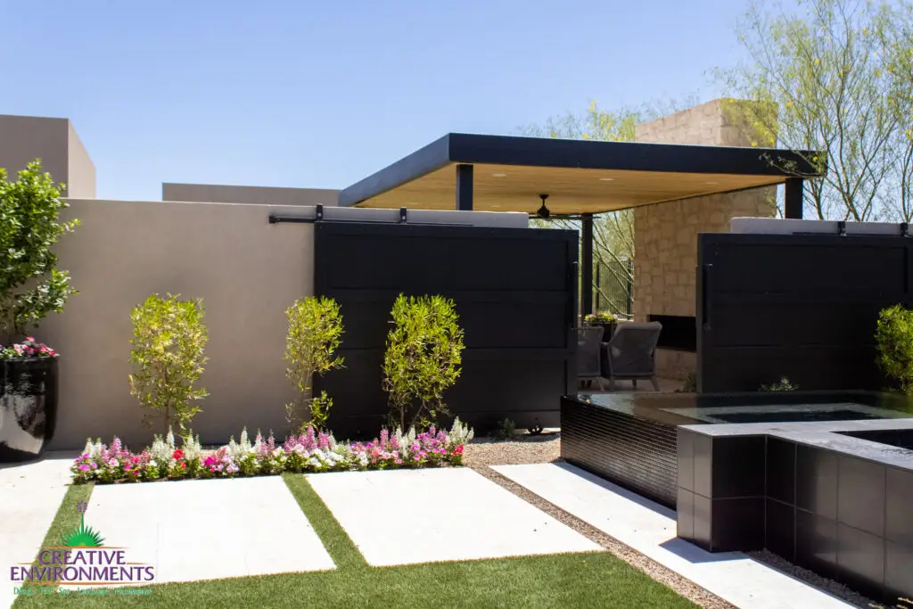 Custom backyard design with metal entry gate, metal shade structure and raised hot tub.