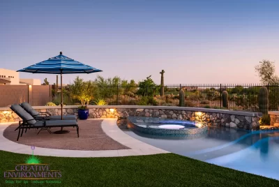 Custom backyard design with natural stone retention wall, curved pool and spa within pool.