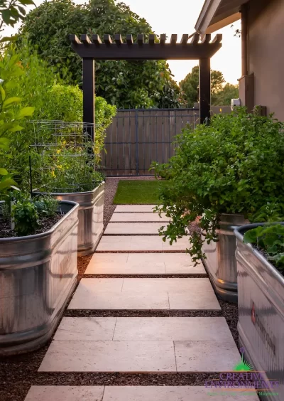 Custom backyard design with trellis archway, galvanized planters and natural stone steps.