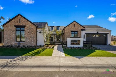 Custom front yard design with multiple grassy areas, built-in fireplace and metal gate.