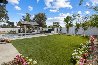 Custom backyard design with annuals, real grass and deco-tile pool.