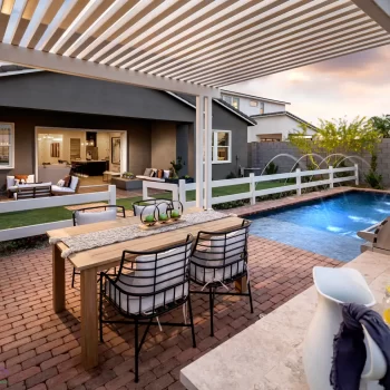 Custom backyard design with white metal shade structure, outdoor dining area and artificial turf.