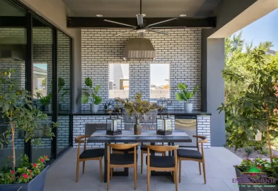 Custom backyard design with outdoor kitchen, outdoor seating areas and large planters.