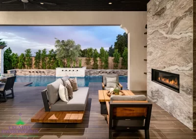 Custom backyard design with marble fireplace, metal water scupper feature and privacy hedges.
