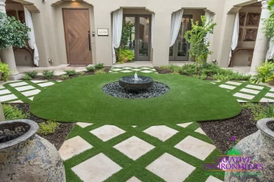 Custom backyard design with artificial turf pattern, black water feature and black beach pebbles.